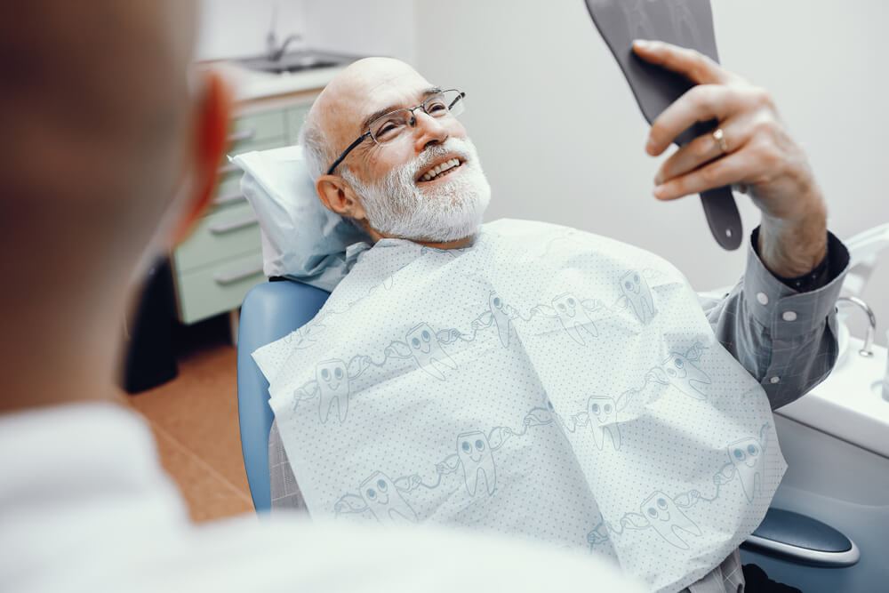 Male patient checking smile in handheld mirror