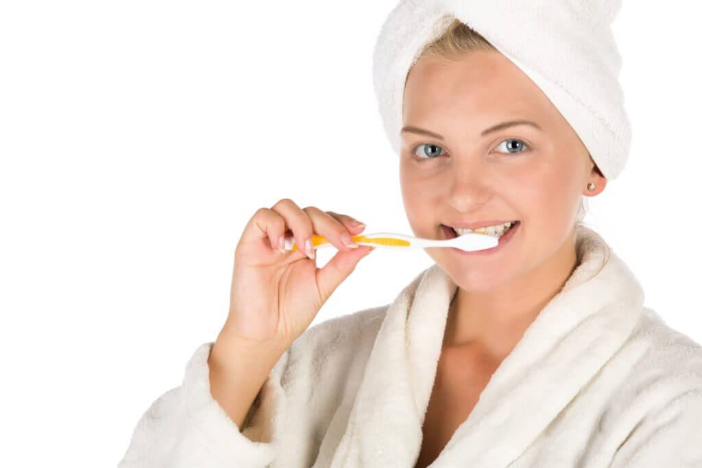 Woman in bathrobe brushing her teeth