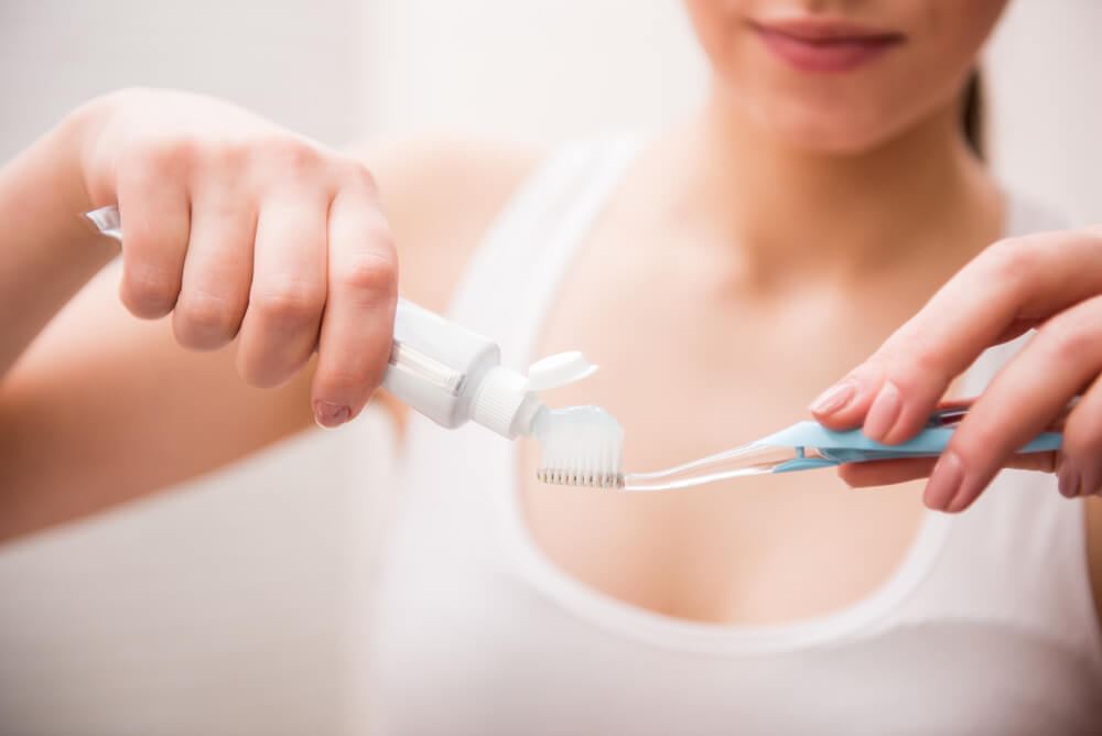 Woman squeezing toothpaste onto a toothbrush