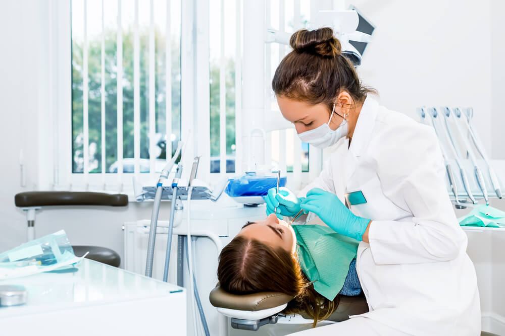 Female dentist performing checkup for female patient