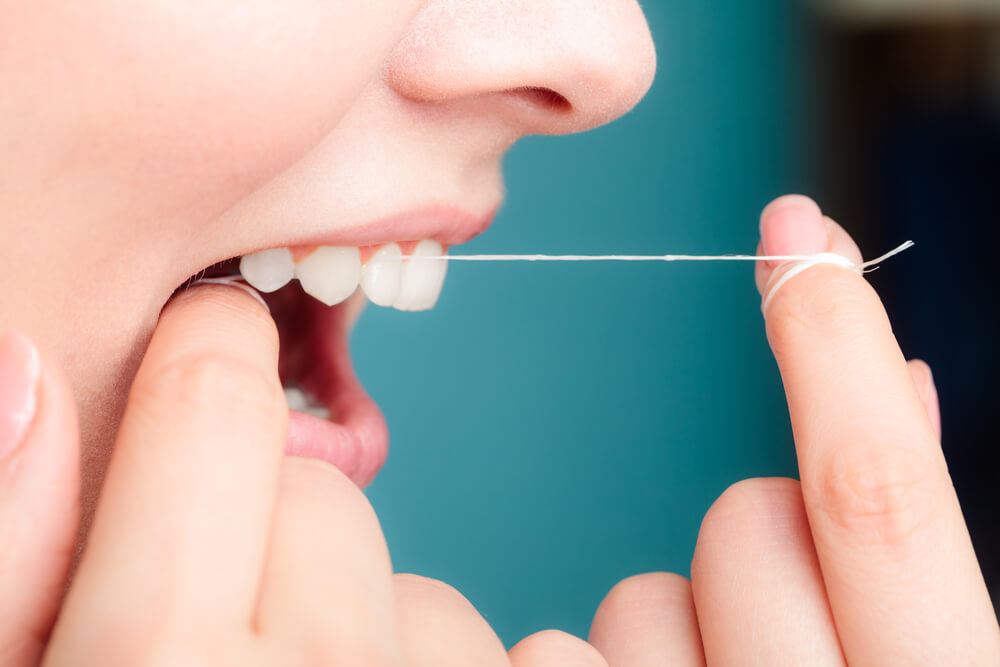 Woman flossing her teeth incorrectly