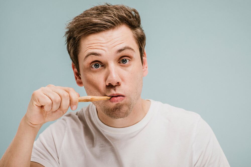 Man in white shirt brushing his teeth