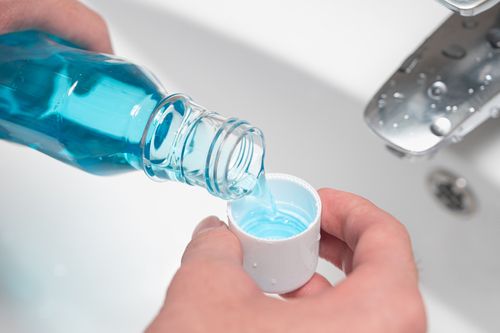 Pouring mouthwash in lid.