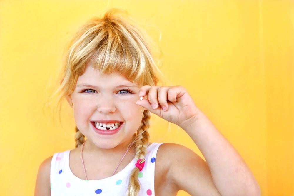 Little girl holding her lost tooth