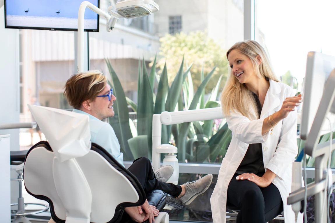Toothbar team member discussing treatment plan with smiling patient inside bright, modern operatory in Austin, TX