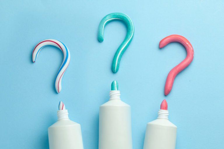Toothpaste tube and streams of toothpaste in shape of question marks