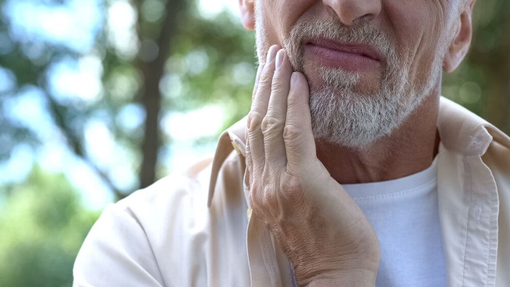 Bearded man with toothache rubbing his jaw