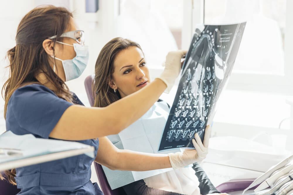 Female dentist showing sheet of X-rays to female patient