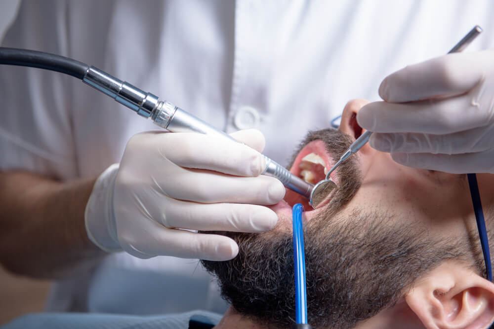 Male patient having teeth cleaned and examined by dentist