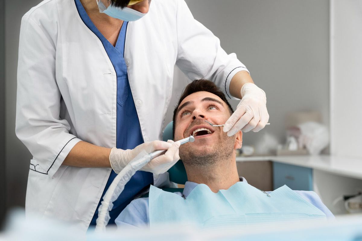 Dentist performing a deep dental cleaning on a male patient, illustrating the thorough cleaning process for preventing gum disease