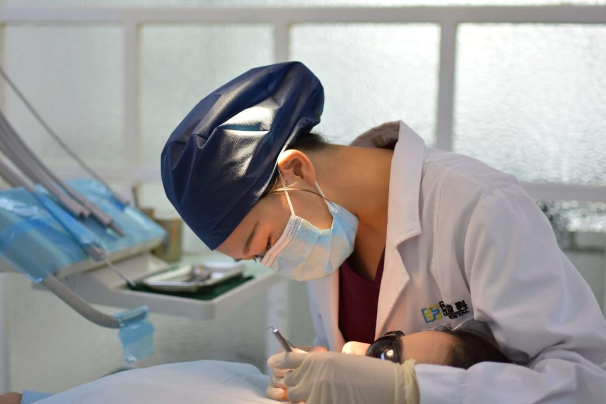 Female dentist with mask placing a dental crown