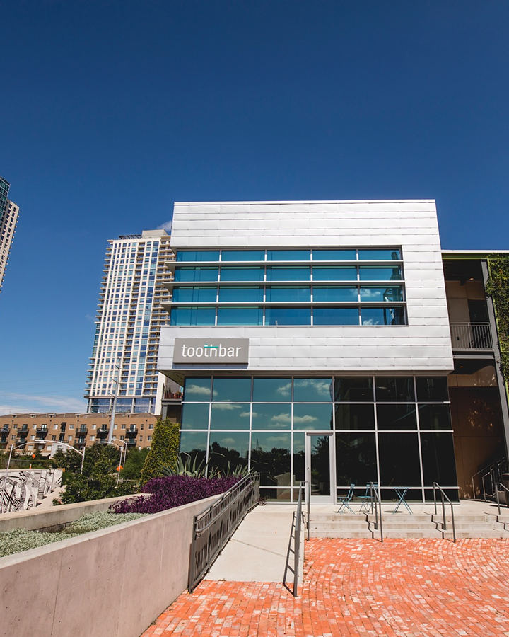 The Toothbar building in the Seaholm District, with glass and metal panels, a green wall and downtown towers