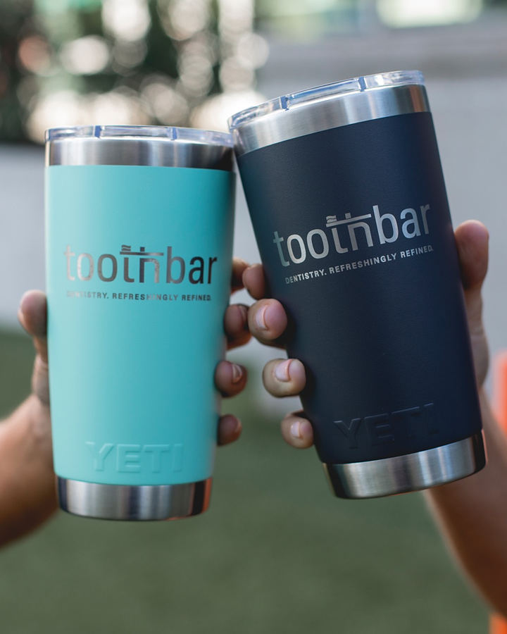 Two hands toasting with Toothbar tumblers in teal and navy