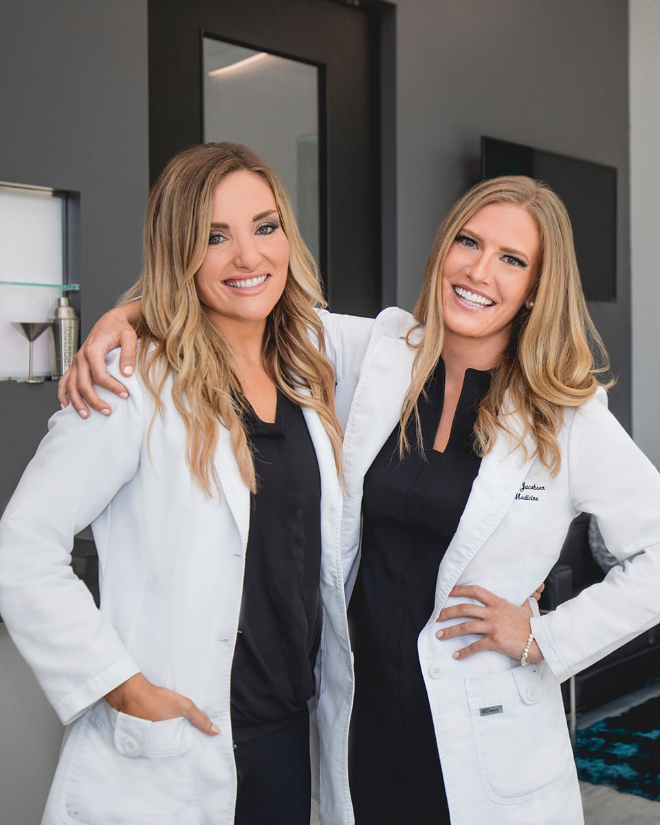 Toothbar founders Dr. Kimberley Barclay and Dr. Lauren Jacobsen in white coats, with the Toothbar logo on the wall behind them