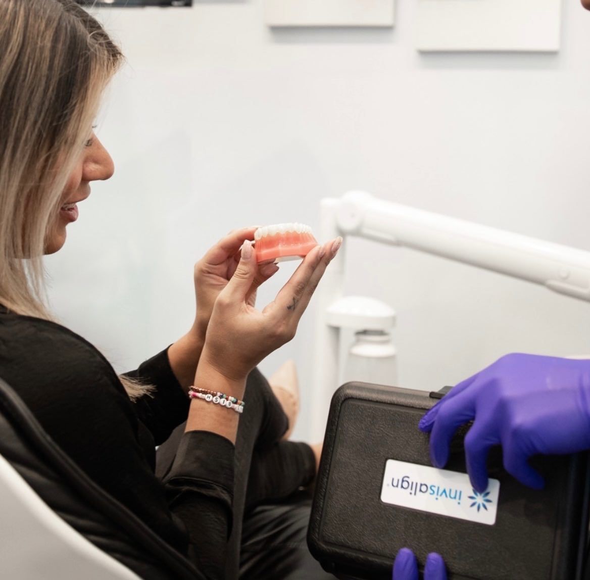 Female patient looking at model of teeth in hand