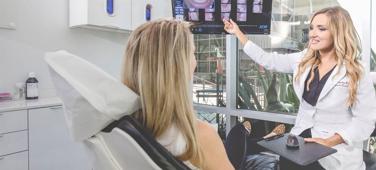 Female dentist showing images of teeth to female dental patient